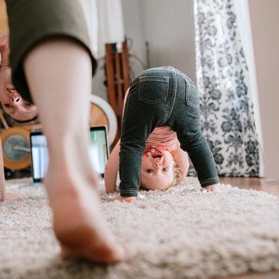 Mor og barn gjør yoga på et mykt teppe hjemme