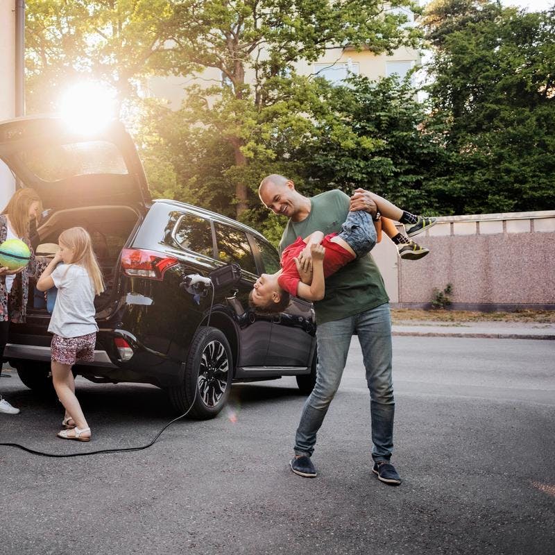 Leken familie foran deres elektriske bil