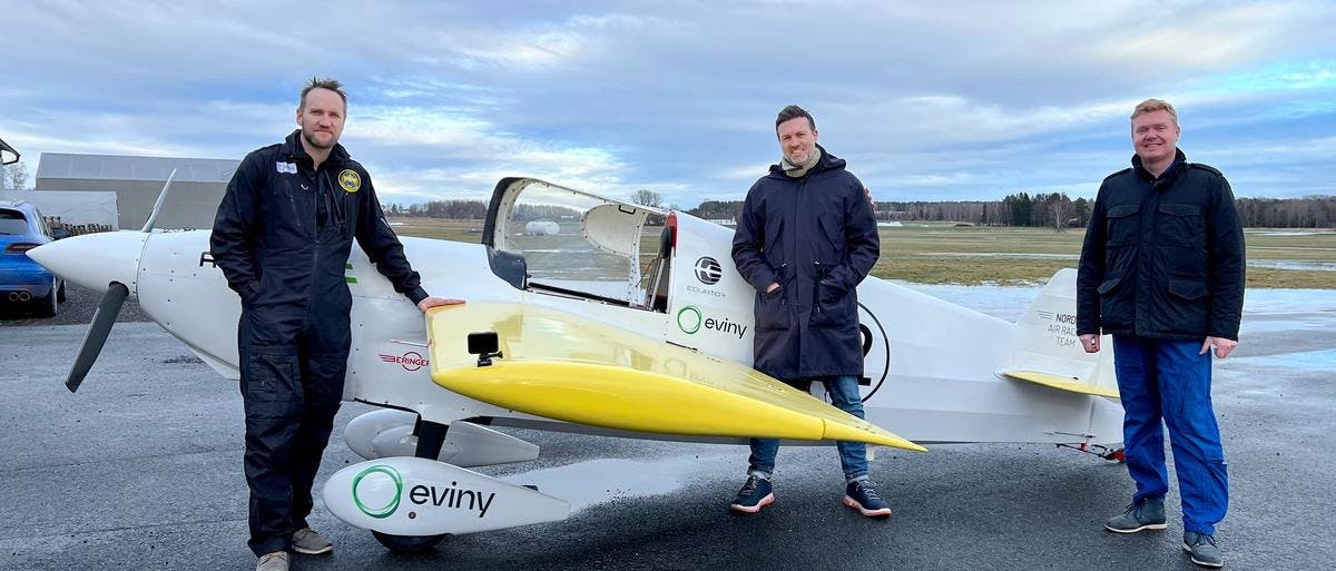 Tre personer står foran verdens første helelektriske racingfly.
